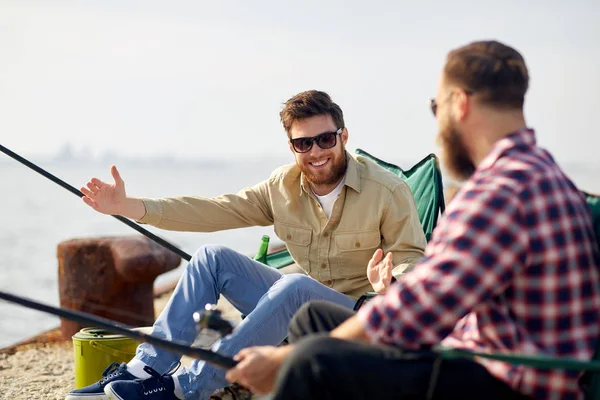 Felizes amigos do sexo masculino com hastes falando sobre pesca — Fotografia de Stock