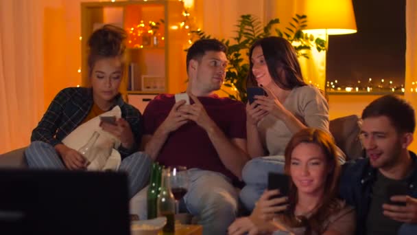 Друзья со смартфоном смотрят телевизор дома — стоковое видео