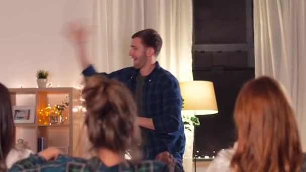 Счастливые друзья, играющие шарады дома вечером — стоковое видео