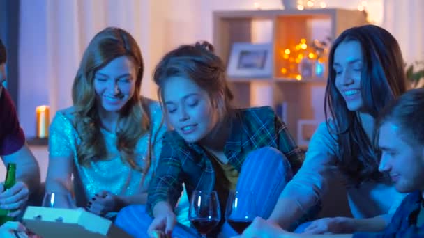 Друзья едят пиццу и пьют вино дома — стоковое видео