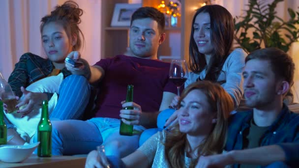 Przyjaciele z napojami i przekąskami, oglądania telewizji w domu — Wideo stockowe