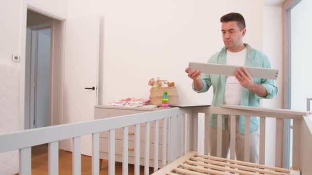 Πατέρας με tablet pc συναρμολόγηση κρεβατιού μωρού στο σπίτι — Αρχείο Βίντεο