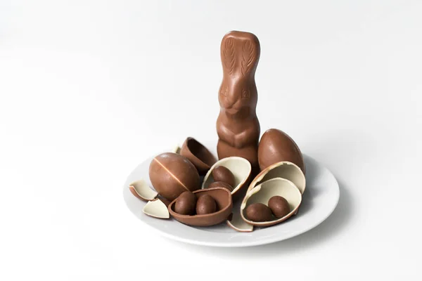 Chocolade konijn, eieren en snoepjes op wit bord Stockfoto