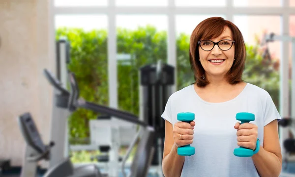 Mujer mayor con pesas haciendo ejercicio en el gimnasio —  Fotos de Stock