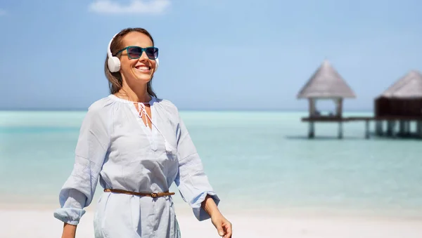 Frau mit Kopfhörern läuft am Sommerstrand entlang — Stockfoto