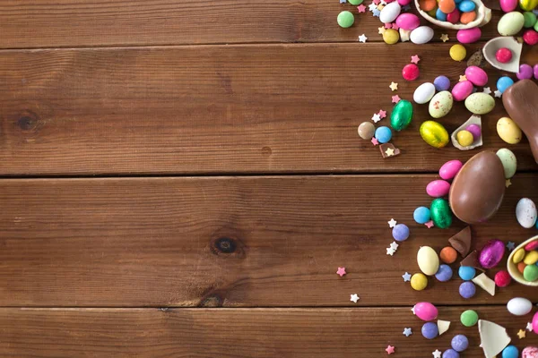 Ovos de chocolate e gotas de doces na mesa de madeira — Fotografia de Stock