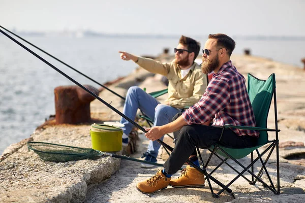 Boldog barátok horgászbotokkal a mólón Stock Kép