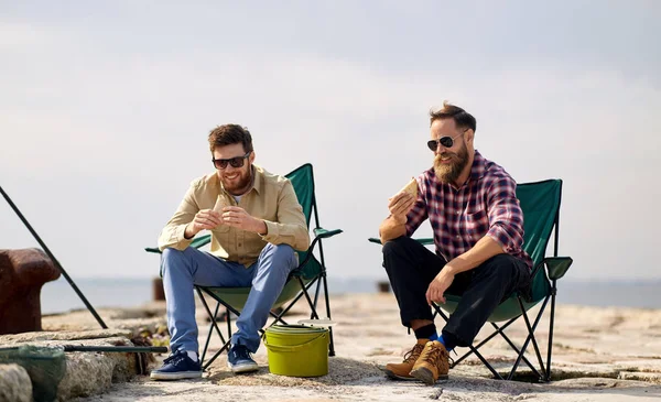 Amis heureux pêche et manger des sandwichs — Photo