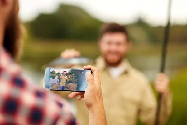 Friend photographing fisherman by smartphone — Stock Photo, Image