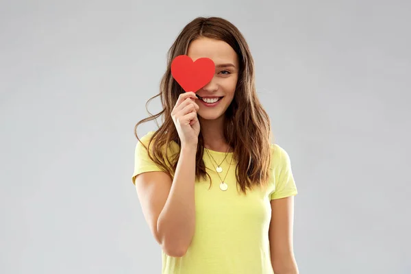 Uśmiechający się nastolatkę, obejmujące jej oko przez czerwone serce — Zdjęcie stockowe