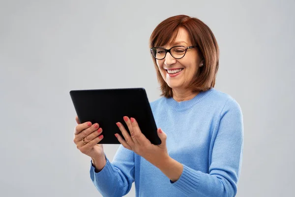 Mulher sênior em óculos usando computador tablet — Fotografia de Stock