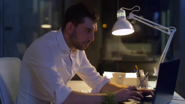 Бизнесмен с ноутбуком и кофе в ночном офисе — стоковое видео