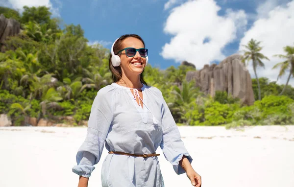Kvinna med hörlurar promenader längs sommar strand — Stockfoto