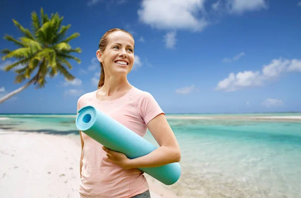 Feliz mulher sorridente com tapete de exercício sobre a praia — Fotografia de Stock