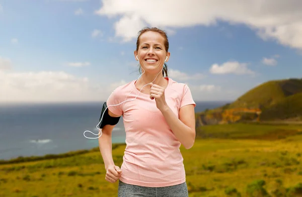 Mujer con auriculares y brazalete corriendo al aire libre —  Fotos de Stock