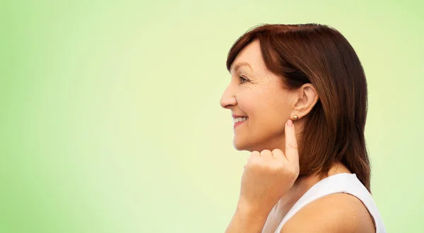Leende senior kvinna som pekar på hennes örhänge — Stockfoto