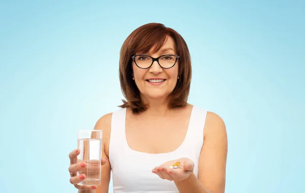 Mujer mayor con vaso de agua y pastillas —  Fotos de Stock