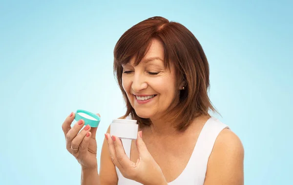 Sonriente mujer mayor con tarro de crema —  Fotos de Stock