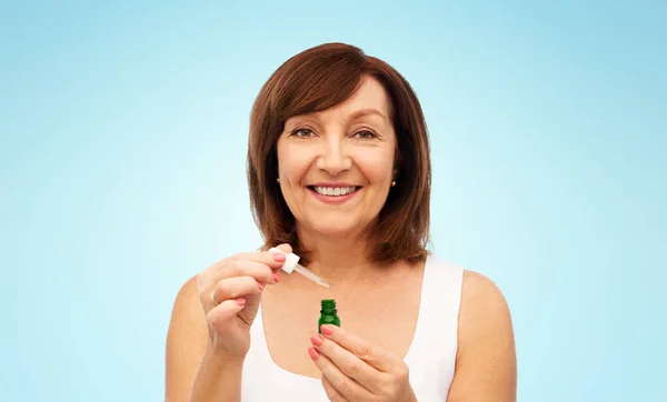 Lachende senior vrouw met fles serum — Stockfoto