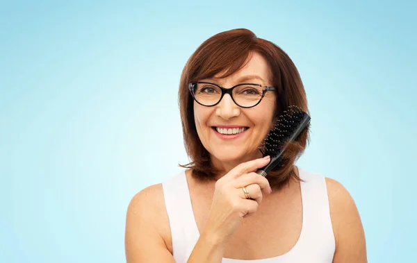 Портрет пожилой женщины в очках, расчесывающей волосы — стоковое фото