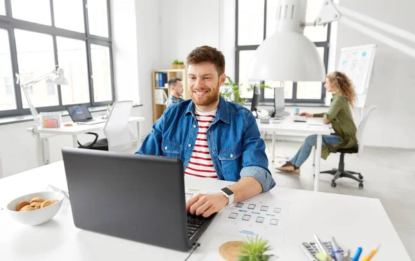 Ofiste çalışan dizüstü bilgisayar ile yaratıcı adam gülümseyen — Stok fotoğraf