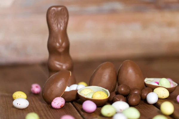 Uova di cioccolato, coniglietto pasquale e caramelle su legno — Foto Stock