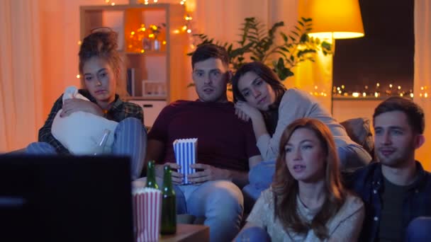Друзья с пивом и попкорном смотрят телевизор дома — стоковое видео