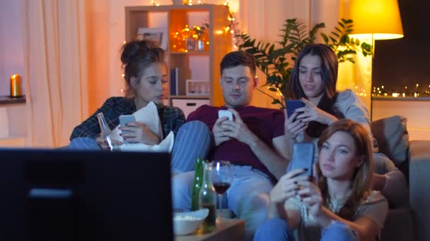 Amigos con smartphone viendo la televisión en casa — Vídeo de stock