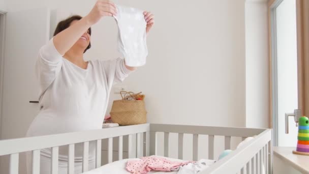 Szczęśliwy w ciąży kobieta ustawienie ubrania dla dzieci w domu — Wideo stockowe