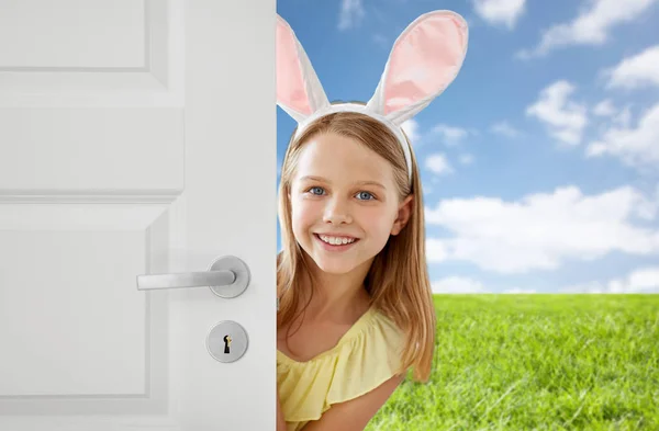 Menina feliz com orelhas de coelho Páscoa espreitando para fora da porta — Fotografia de Stock