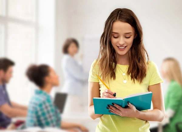 Adolescente estudante menina escrevendo para notebook na escola — Fotografia de Stock
