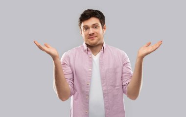 young man shrugging over grey background clipart