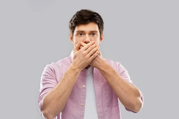 Chockad ung man som täcker munnen av händer — Stockfoto