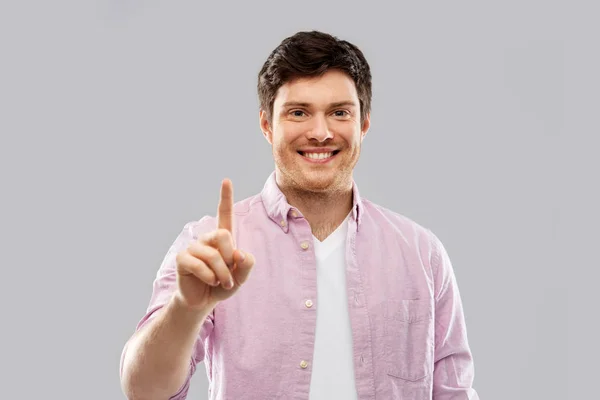 Junger Mann zeigt einen Finger über grauem Hintergrund — Stockfoto