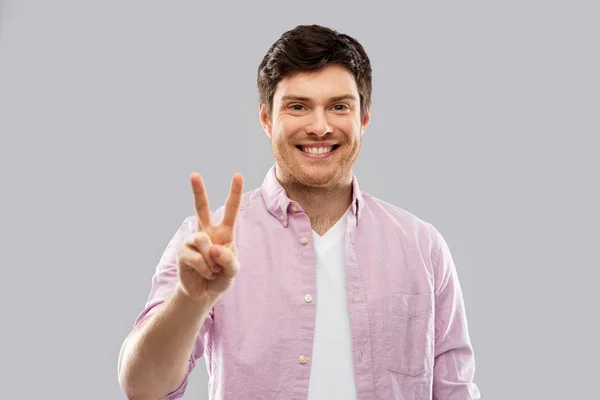 Νεαρός άνδρας που δείχνει δύο δάκτυλα ή το χέρι σήμα της ειρήνης — Φωτογραφία Αρχείου