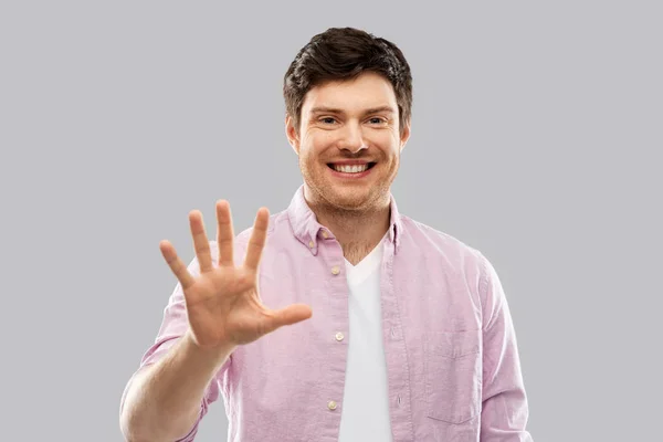 Joven mostrando cinco dedos sobre gris — Foto de Stock