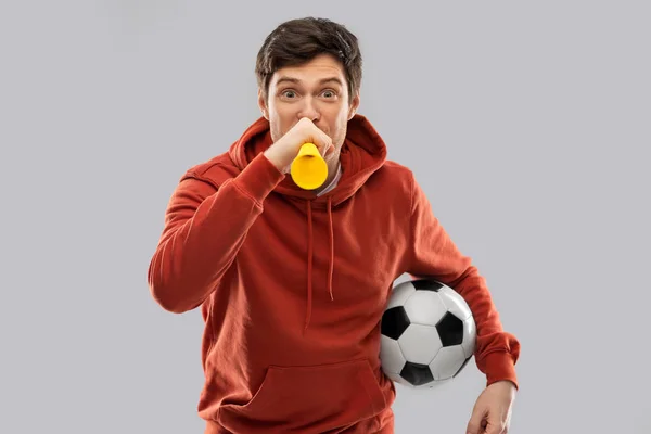 Футбольный болельщик с футбольным мячом, дующий в рог — стоковое фото