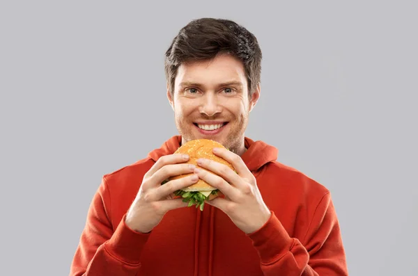 Happy young man eating hamburger — Stock Photo, Image