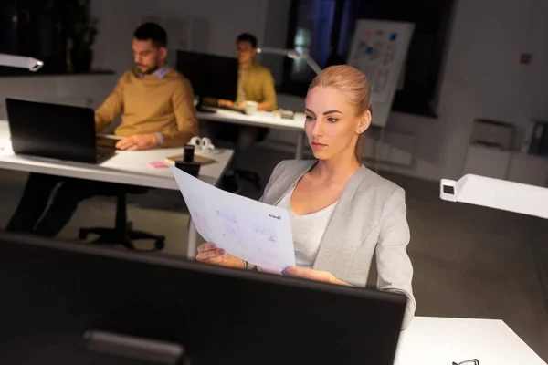 Diseñador trabajando con papeles en la oficina nocturna — Foto de Stock