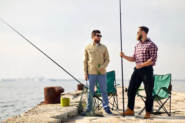 Amigos felizes com varas de pesca e cerveja no cais — Fotografia de Stock