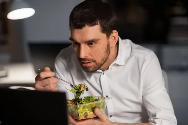 Бизнесмен с компьютером едят в ночном офисе — стоковое фото