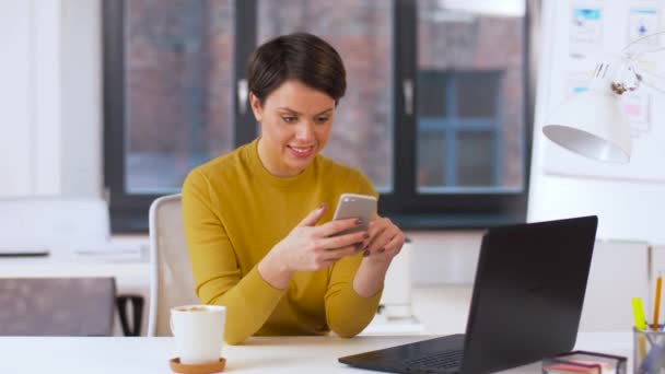 Mujer de negocios sonriente usando teléfono inteligente en la oficina — Vídeos de Stock