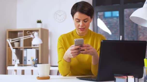 Glimlachende zakenvrouw met smartphone op kantoor — Stockvideo