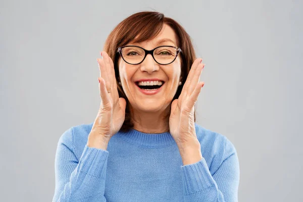 Senior vrouw in glazen roepen over grijs — Stockfoto