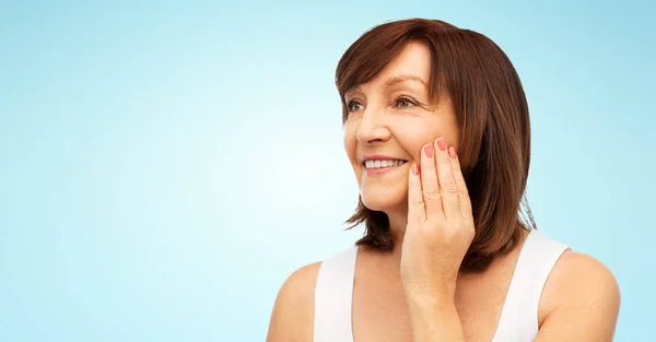 Portrait de femme âgée souriante touchant son visage — Photo