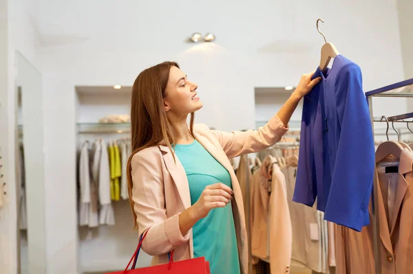 Gelukkig vrouw kiezen kleding in kleding winkel — Stockfoto