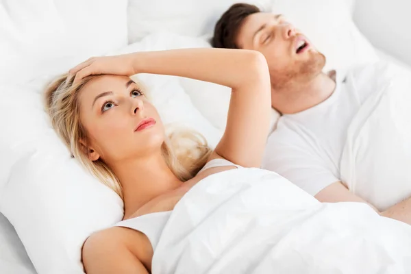 Unhappy woman in bed with snoring sleeping man — Stock Photo, Image