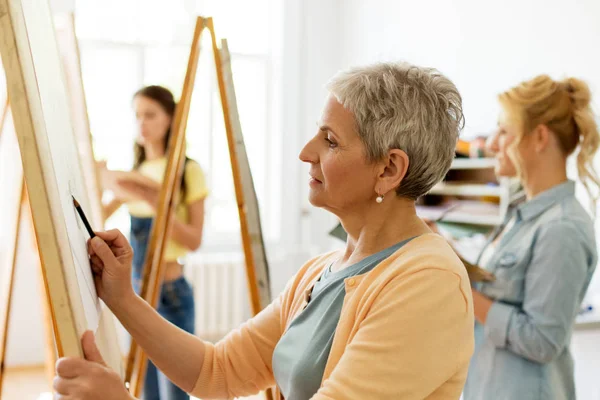 Mujer mayor dibujo en caballete en el estudio de la escuela de arte —  Fotos de Stock