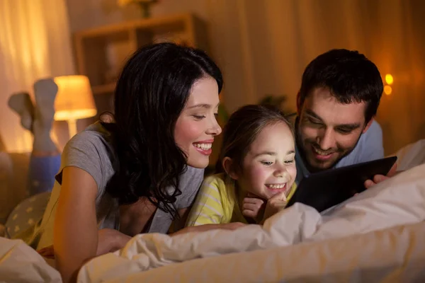 Family with tablet pc in bed at night at home — Stock Photo, Image