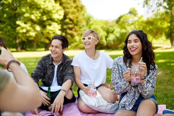 Amigos felices con bebidas en el picnic en el parque de verano —  Fotos de Stock